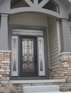 A glass entry door on a home with gray lap siding.